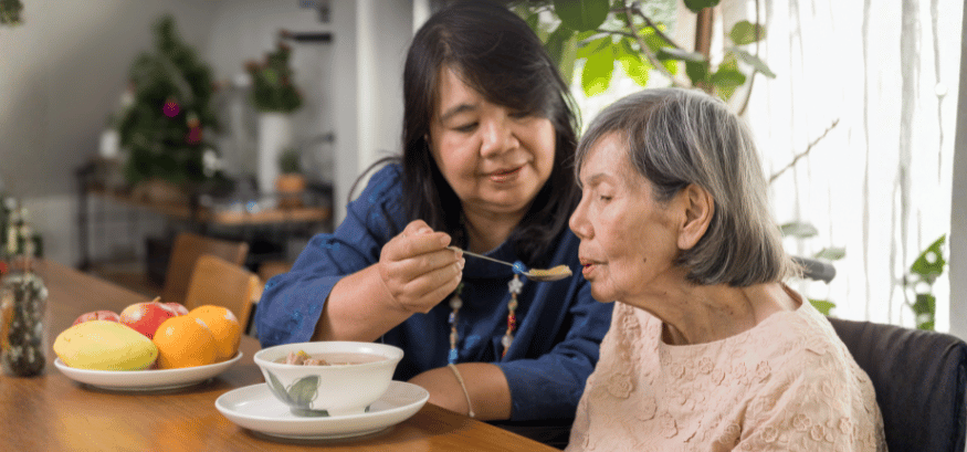 female caregiver feeding elderly woman