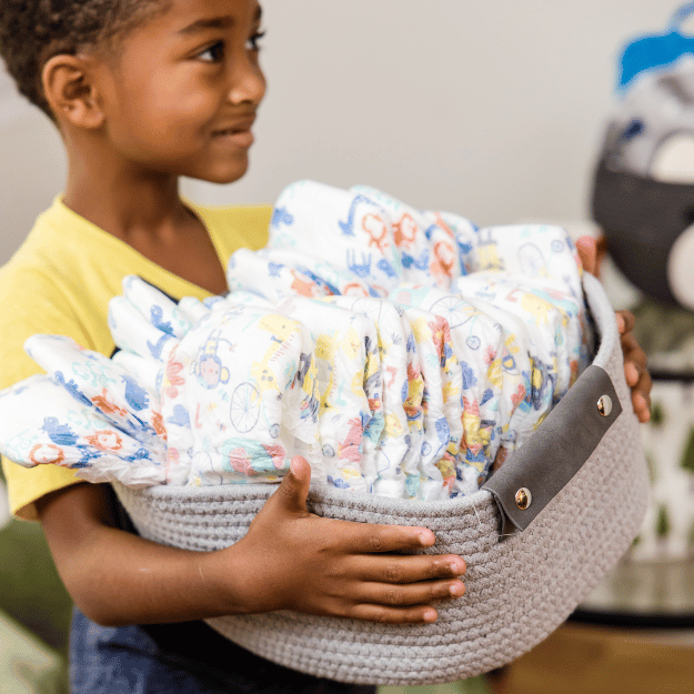 young boy holding a basket of diapers