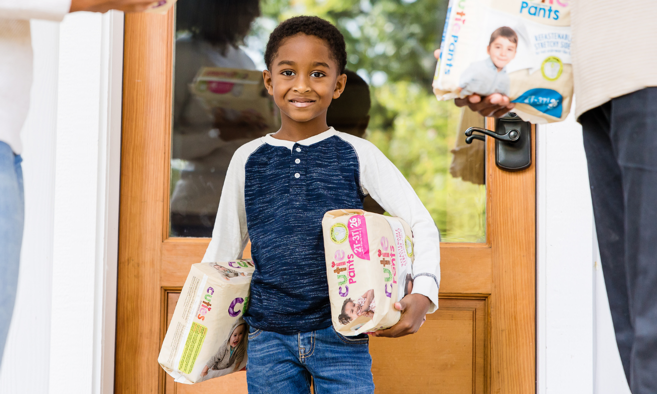 young boy holding packs of diapers