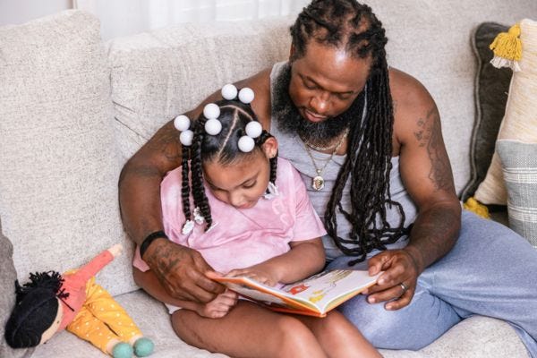 Father caring for his daughter and reading a book