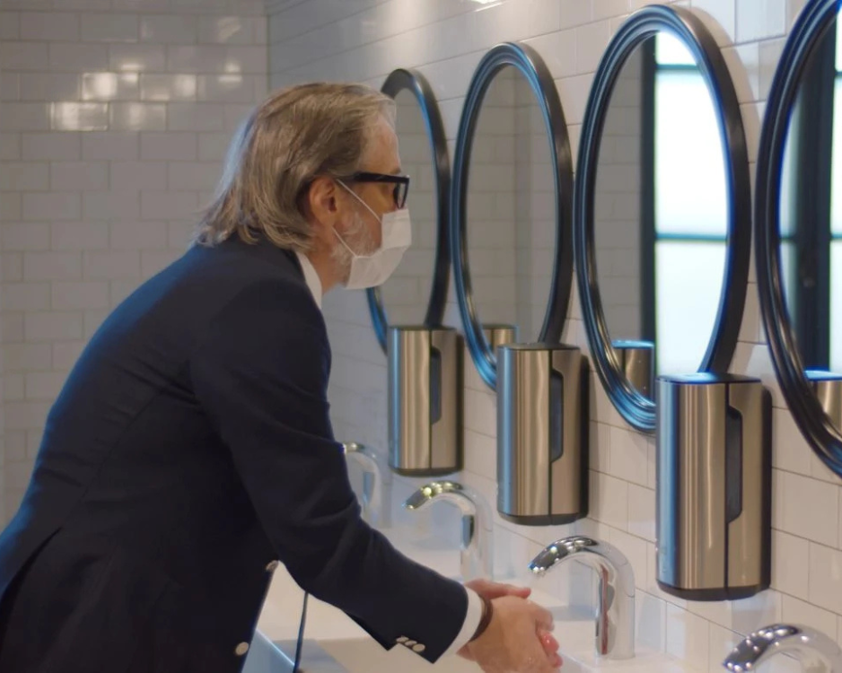 man wearing a covid mask washing hands