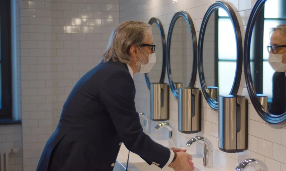 man wearing a covid mask washing hands