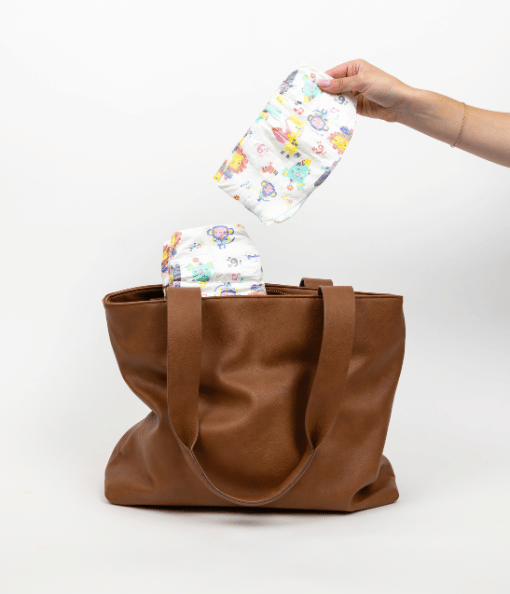 hand pulling diaper out of a leather bag