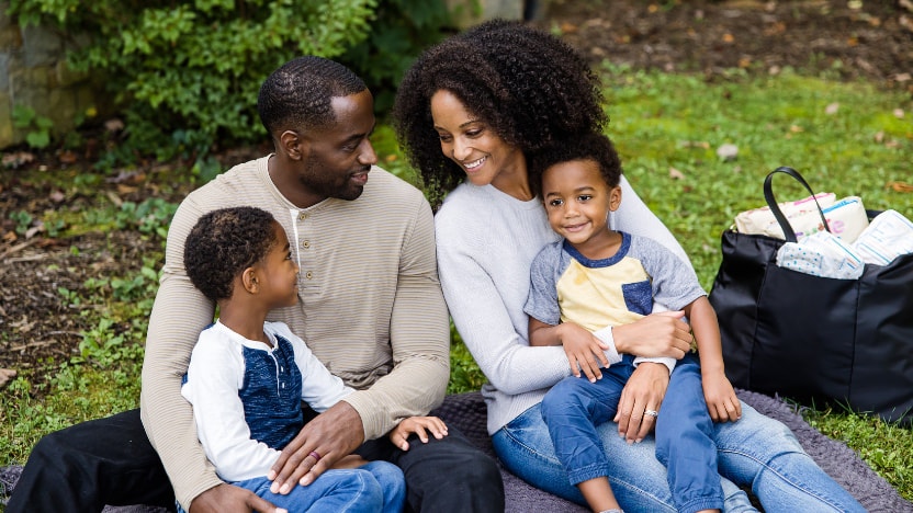 African American family of four in park on blanket with diaper bag