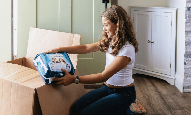 girl unboxing a youth pull-on delivery from aeroflow