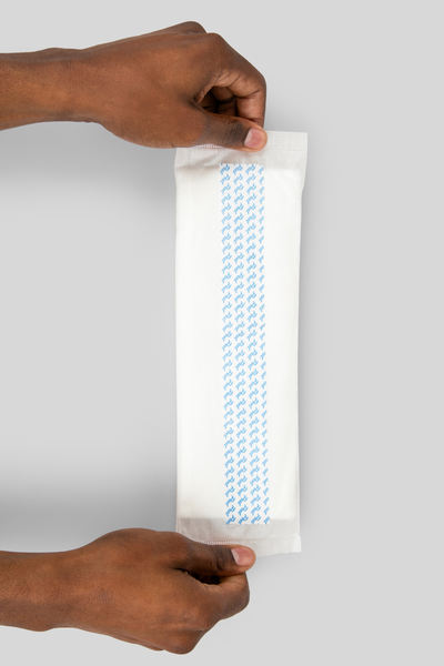 hands holding a booster pad displaying the adhesive back