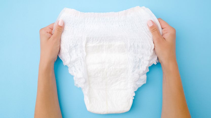 hands holding an adult diaper against a blue background