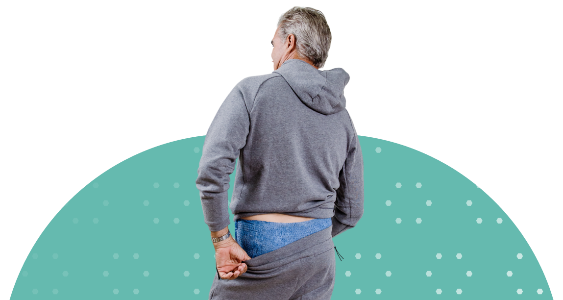 white adult man pulling pants up with adult diaper on