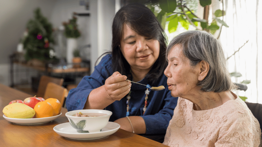 female caregiver feeding elderly woman