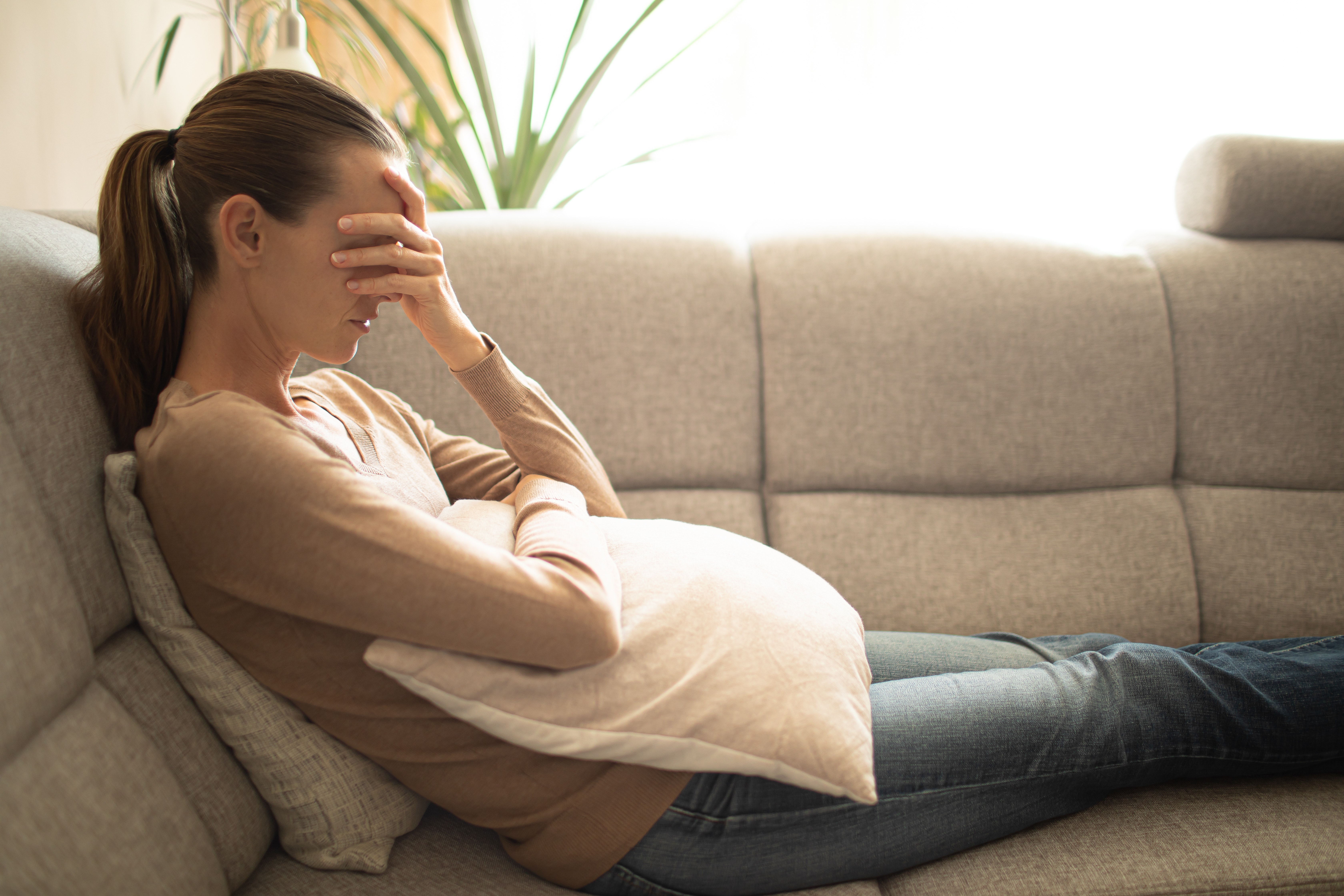 tired woman on couch with hand over face