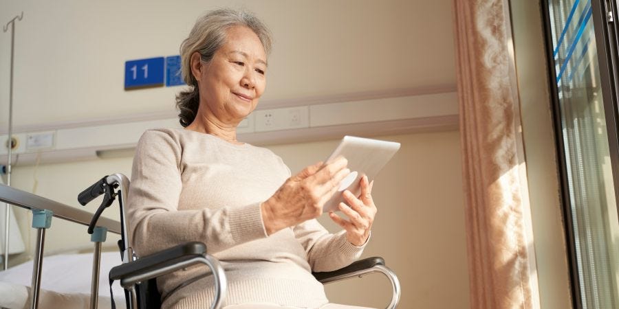Older woman sitting in a wheelchair holding an electronic device.